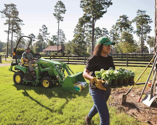 Two people building a flowerbed with a john deere tractor