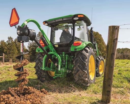 A John Deere tractor with a post-holer attachment