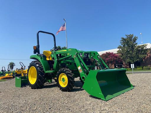 John Deere compact tractor against a bright, clear blue sky