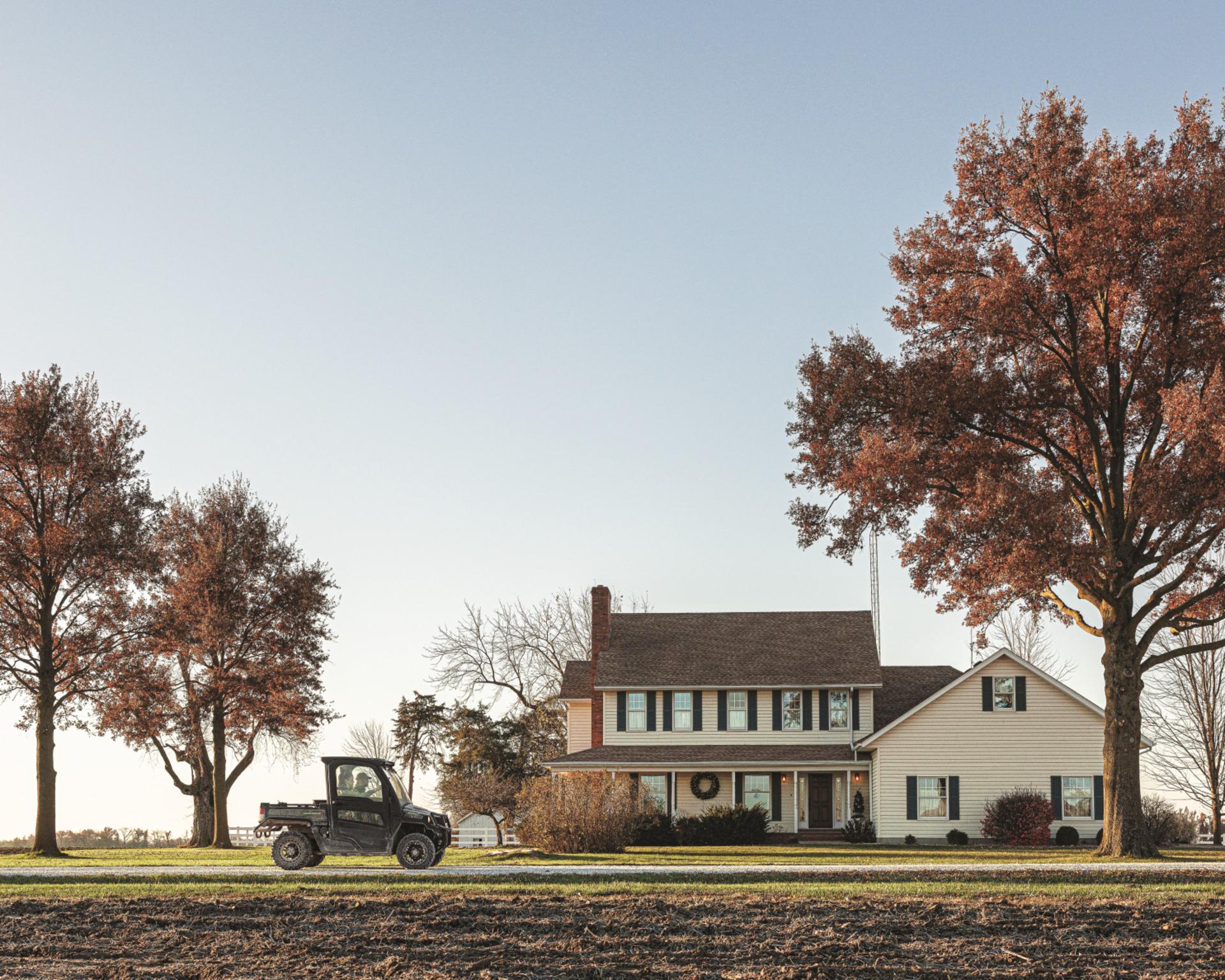 A John Deere Gator XUV835M in front of a home.