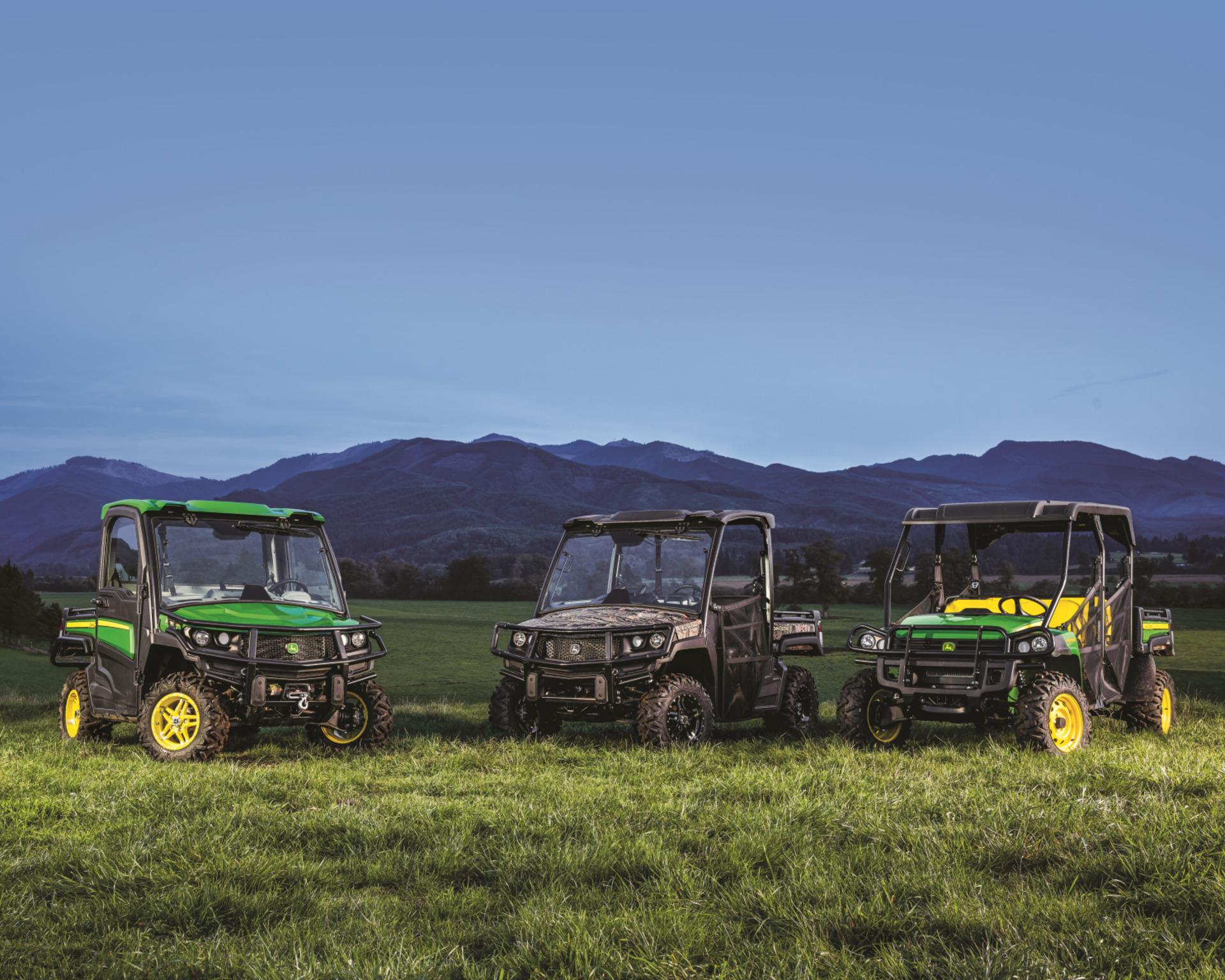 John Deere Gator XUV group shot in front of mountains.