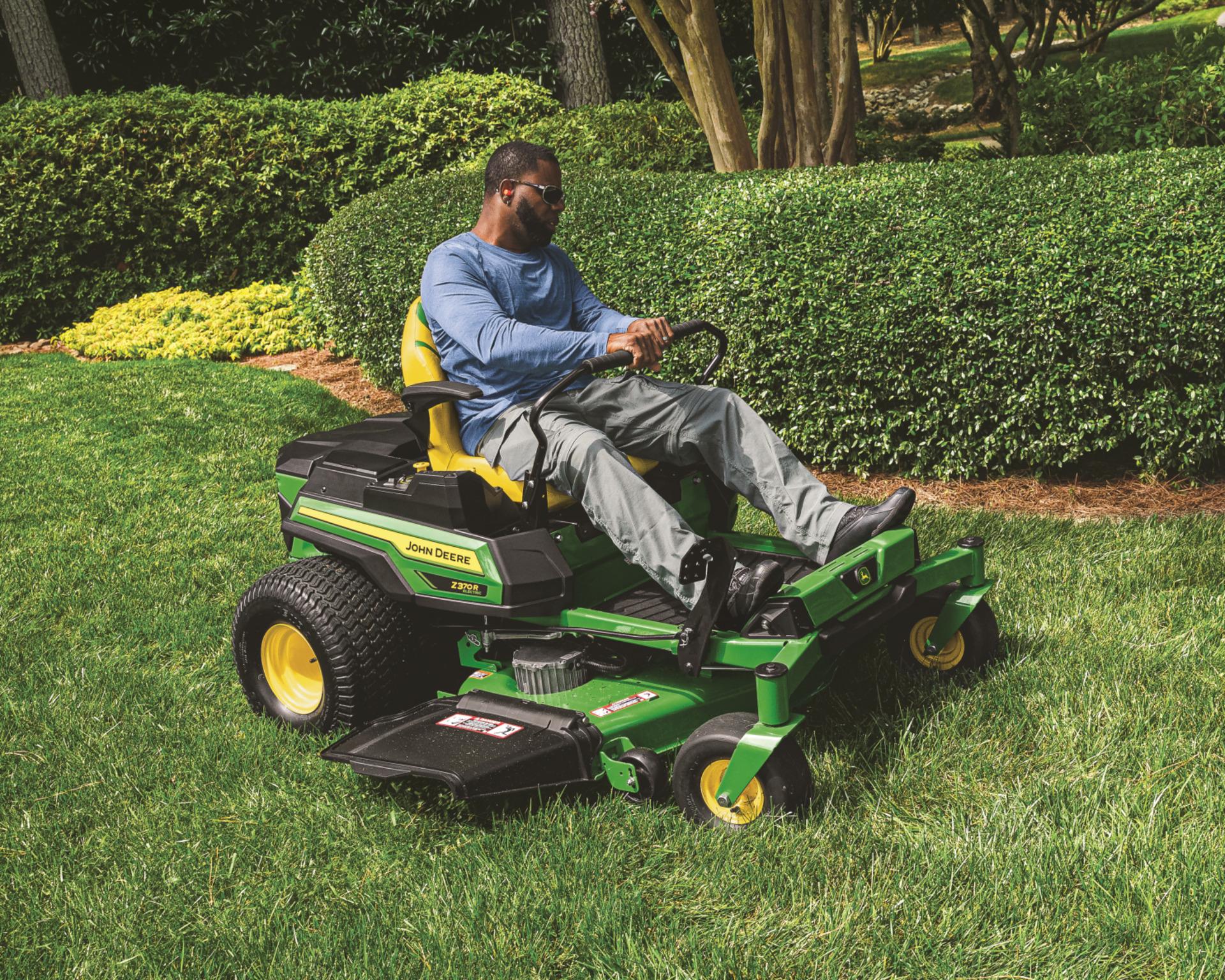 A John Deere Z370R zero-turn mower with a worker mowing a lawn.