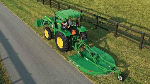 john deere tractor with a rotary cutter mowing the shoulder of a road