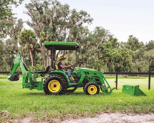 BKA rental John Deere tractor with a canopy, backhoe and loader on a green field